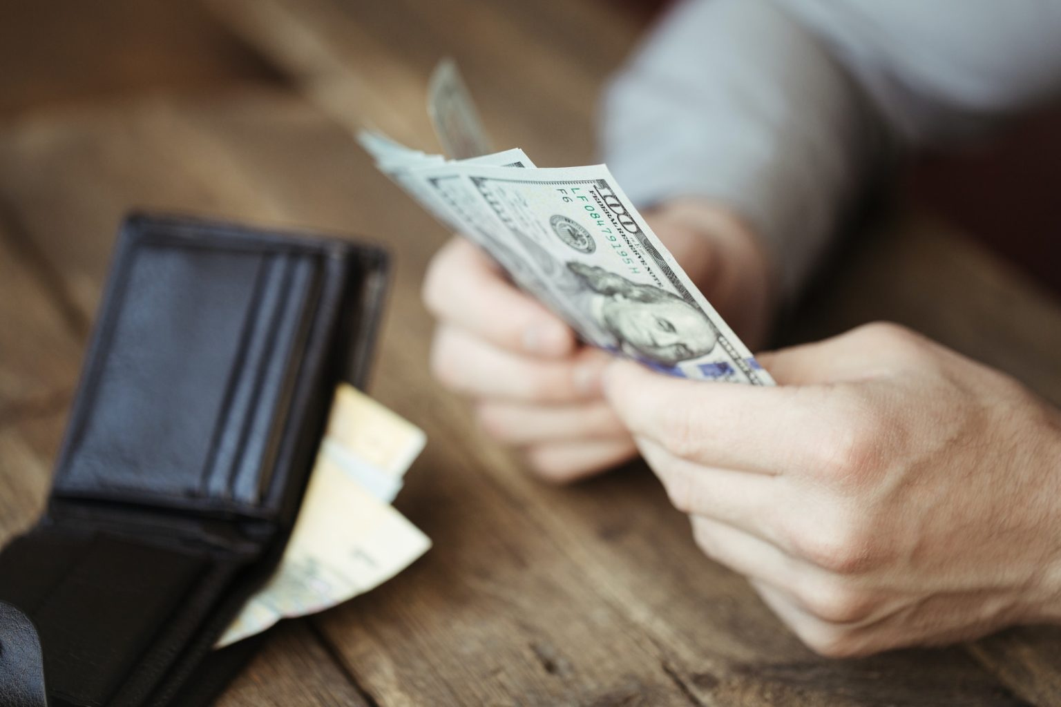 Male hands holding dollar banknote on old wooden background