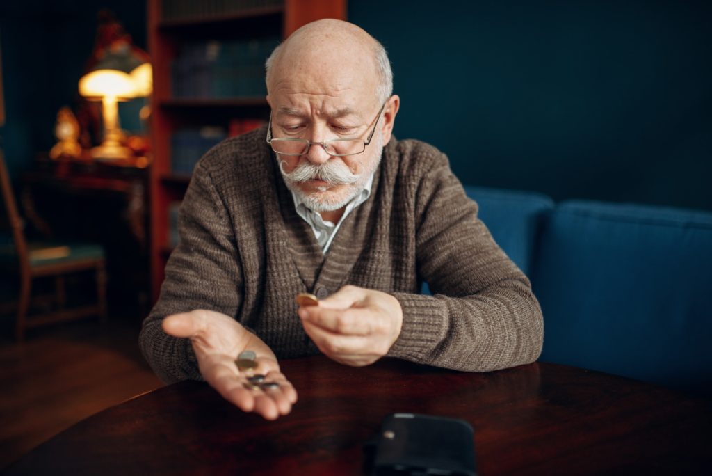 Pour elderly man holds coins